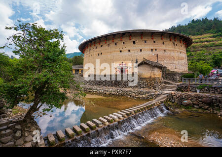 La Chine, la province de Fujian, tulou à un barrage dans un village Hakka Banque D'Images