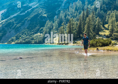 Autriche, Tyrol, randonneur au lac Seebensee marcher dans l'eau jusqu'aux chevilles Banque D'Images