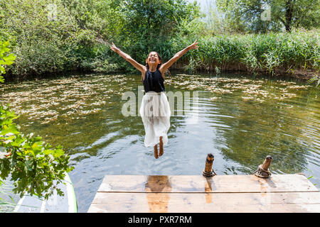 Carefree girl saut dans l'étang Banque D'Images