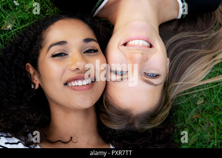 Deux copines se détendre dans un parc, lying on grass Banque D'Images