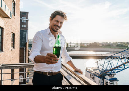 Happy businessman sitting on, boire de la bière Banque D'Images