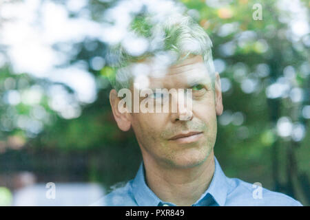 Portrait of smiling young man looking out of window Banque D'Images