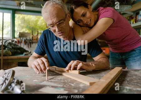 Young woman watching man working in workshop Banque D'Images