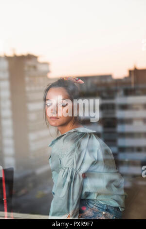 Portrait de jeune femme derrière la vitre d'une réflexion de la ville Banque D'Images
