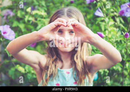 Jeune fille de prendre une forme de coeur avec ses doigts Banque D'Images