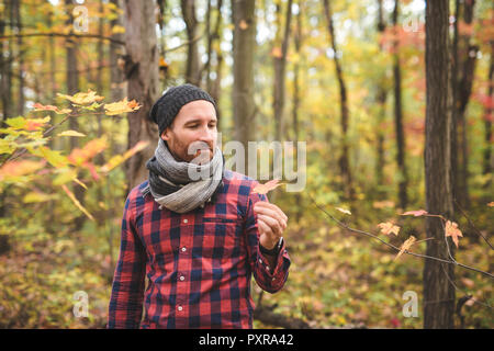 Confiant et beau. Beau jeune homme dans l'arrière-plan et orange feuilles tombées sur le sol Banque D'Images