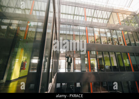 Businessman standing in office building, regardant à travers des lunettes VR Banque D'Images