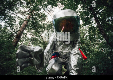 Spaceman explorer la nature, examining plants in forest Banque D'Images