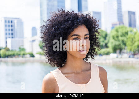 Allemagne, Francfort, portrait de jeune femme avec des cheveux bouclés en face de la rivière Main Banque D'Images