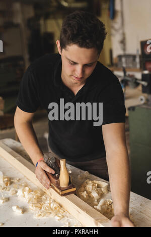 Carpenter using plane sur le morceau de bois dans l'atelier Banque D'Images