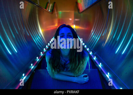 Portrait de jeune femme à éclairage bleu sur les marches de l'escalator lumineux Banque D'Images