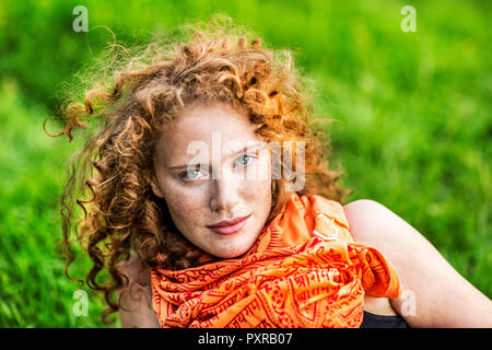 Portrait de jeune femme avec des taches de rousseur cheveux bouclés portant foulard orange rouge Banque D'Images