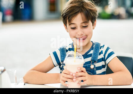 Portrait de petite fille avec de délicieux milk-shake à la fraise au café de la chaussée Banque D'Images