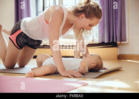 Mère jouant avec son bébé sur un tapis de yoga pendant l'entraînement Banque D'Images