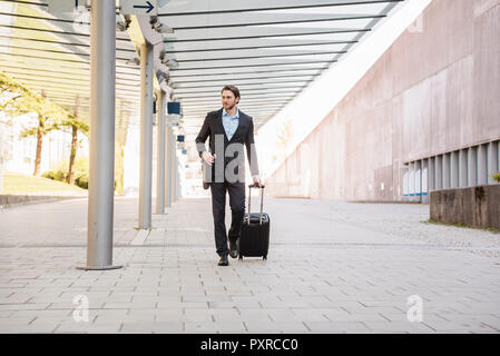Businessman en mouvement poussant rolling suitcase Banque D'Images