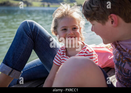 Autriche, Tyrol, Walchsee, happy brother and sister smiling at les uns les autres au bord de lac Banque D'Images