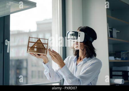 Woman holding miniature d'architecture de maison, à l'aide de lunettes VR Banque D'Images