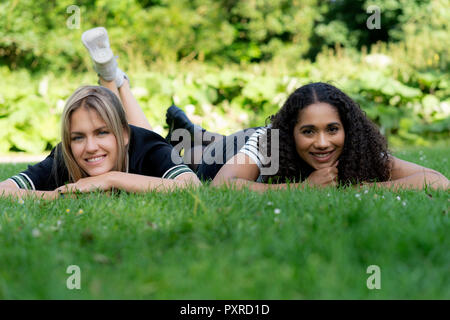 Deux copines se détendre dans l'herbe dans un parc Banque D'Images