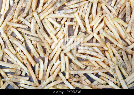 Les lamelles de pommes de terre sur une plaque de cuisson saupoudrée de sel poivre et épices herbes de Provence . C'est le début du processus de la cuisson des viandes Banque D'Images