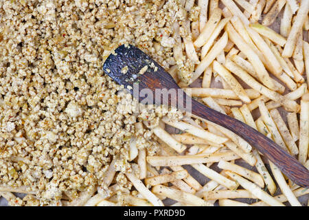 Les lamelles de pommes de terre et de porc haché sur une plaque de cuisson saupoudrée de sel poivre et herbes épices . C'est le début du processus de coo Banque D'Images