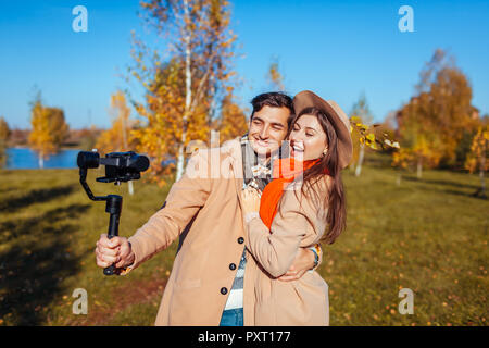 Jeune couple de filmer une vidéo à l'aide de steadicam forêt d'automne. L'homme et la femme les blogueurs s'amuser en plein air Banque D'Images