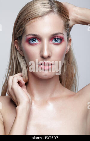 Portrait de belle fille. Jeune femme avec de longs cheveux blonds. Femme posant sur fond gris. Banque D'Images