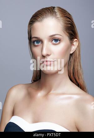 Portrait de belle fille. Jeune femme avec de longs cheveux blonds. Femme en robe noire posant sur fond gris. Banque D'Images