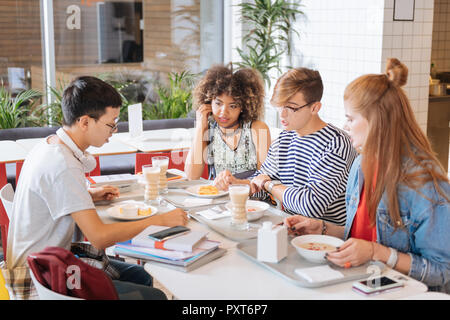 Groupe d'élèves ayant leur dîner dans canteen Banque D'Images