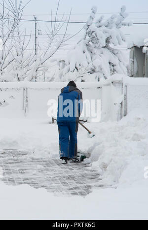 Travailleur avec une pelle efface la neige en hiver Banque D'Images