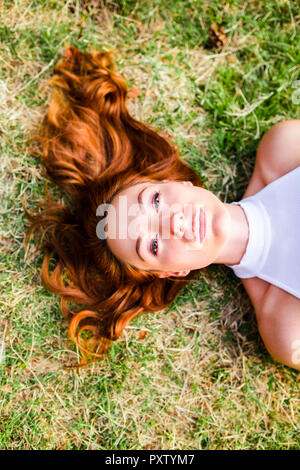 Portrait de jeune femme rousse allongée sur un pré Banque D'Images