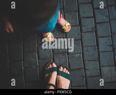 Pieds de petite fille et sa mère debout sur la chaussée en bois, vue du dessus Banque D'Images