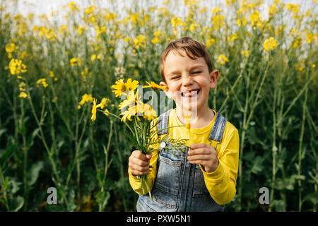 Portrait de petit garçon avec choisi fleurs jaunes dans la nature Banque D'Images