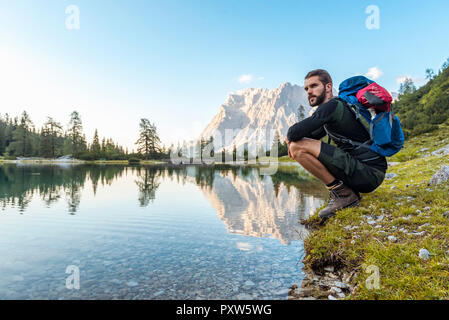 Autriche, Tyrol, randonneur prenant une pause, accroupi au bord du lac Banque D'Images