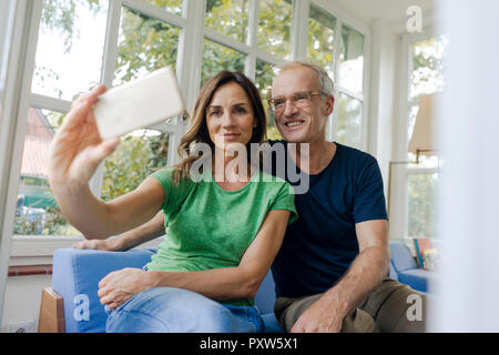 Smiling mature couple prenant une à la maison selfies Banque D'Images