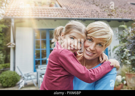 Portrait of smiling mother carrying fille devant leur maison Banque D'Images