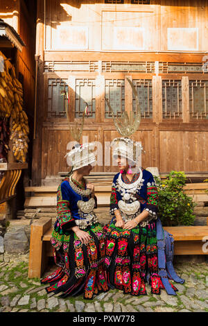 La Chine, Guizhou, deux jeunes femmes Miao souriant portant des vêtements traditionnels et coiffures Banque D'Images