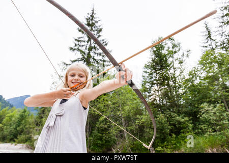 Smiling girl visant avec arc et flèche dans la nature Banque D'Images