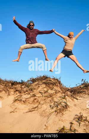 Portugal, Algarve, couple sur la plage de dunes en saut Banque D'Images