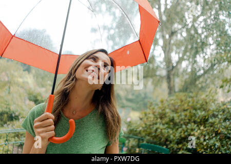 Smiling mature woman under umbrella in rain Banque D'Images