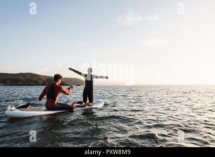 Couple on paddleboard au coucher du soleil Banque D'Images