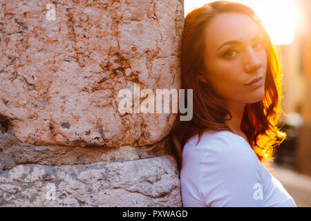 Portrait de femme rousse leaning against wall au coucher du soleil Banque D'Images