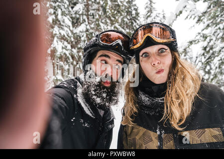 Des selfies happy couple in skiwear grimaçait en hiver forêt Banque D'Images