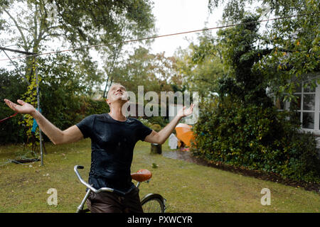 Homme mature avec location bénéficiant d'pluie d'été dans le jardin Banque D'Images