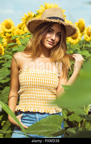 Jeune femme avec un chapeau de paille dans un champ de tournesols Banque D'Images