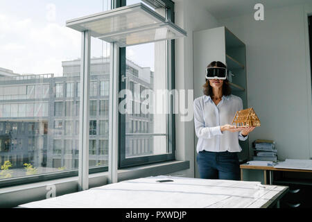 Woman holding miniature d'architecture de maison, à l'aide de lunettes VR Banque D'Images