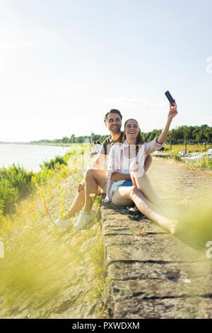 Heureux couple au bord de la rivière en été prendre une selfies Banque D'Images