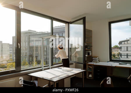 Businesswoman standing in office, à la fenêtre de Banque D'Images