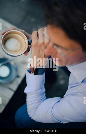 Mature businessman sitting in coffee shop, portant des smart watch Banque D'Images