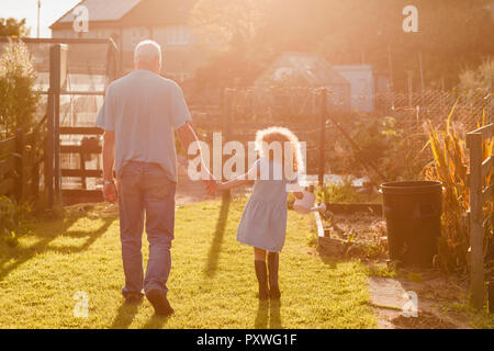 Petite fille main dans la main avec son oncle dans le jardin Banque D'Images