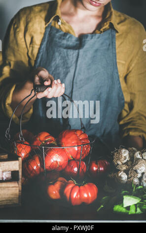 Tablier en lin femme holding basket with heirloom tomatoes Banque D'Images